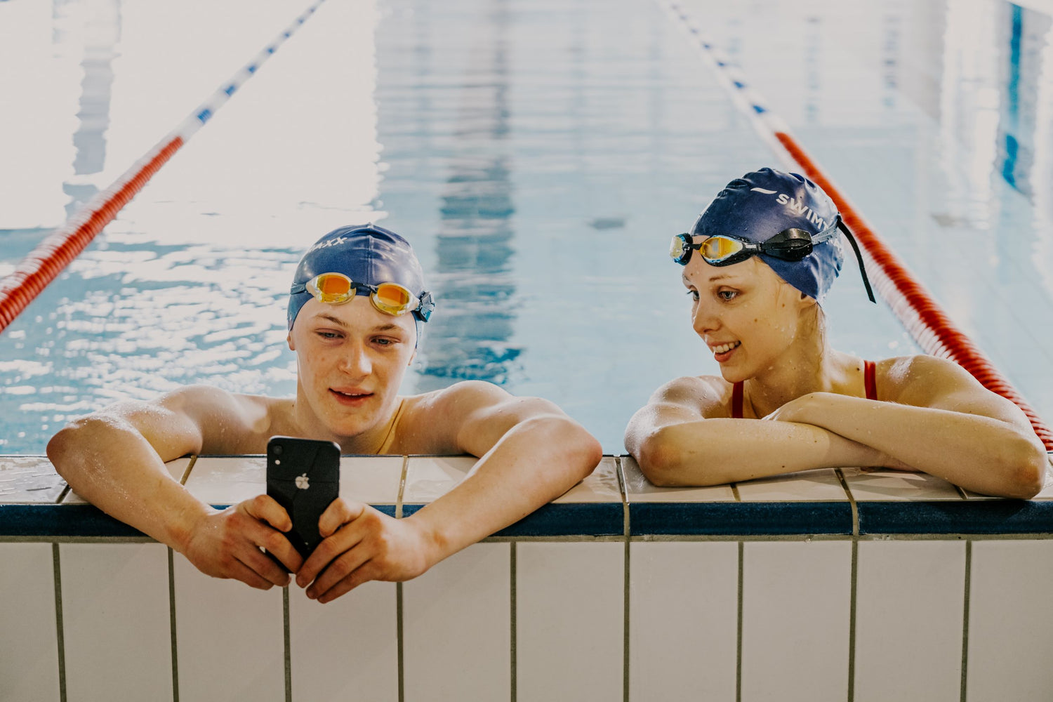 Boy and girl checking Swimtraxx One data during their swim workout on the phone